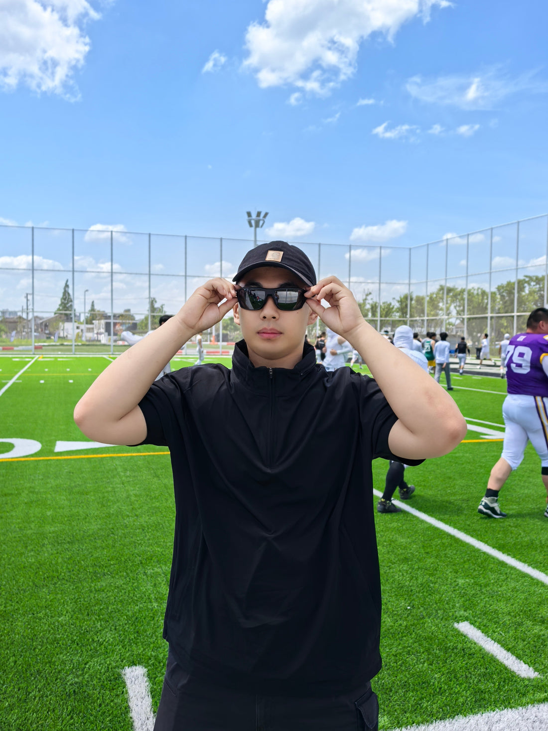 Front view of a black short sleeve coaching top with a standing collar and short zip